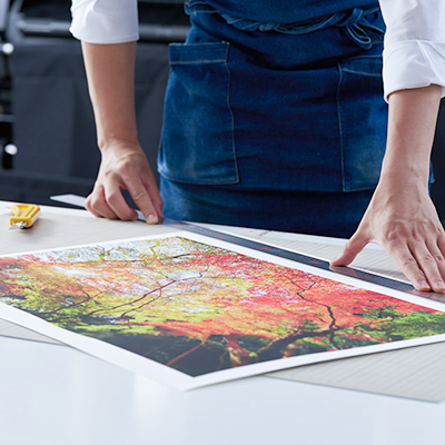 Aflo Gallery staff handling a Japanese autumn forest photography print for framing